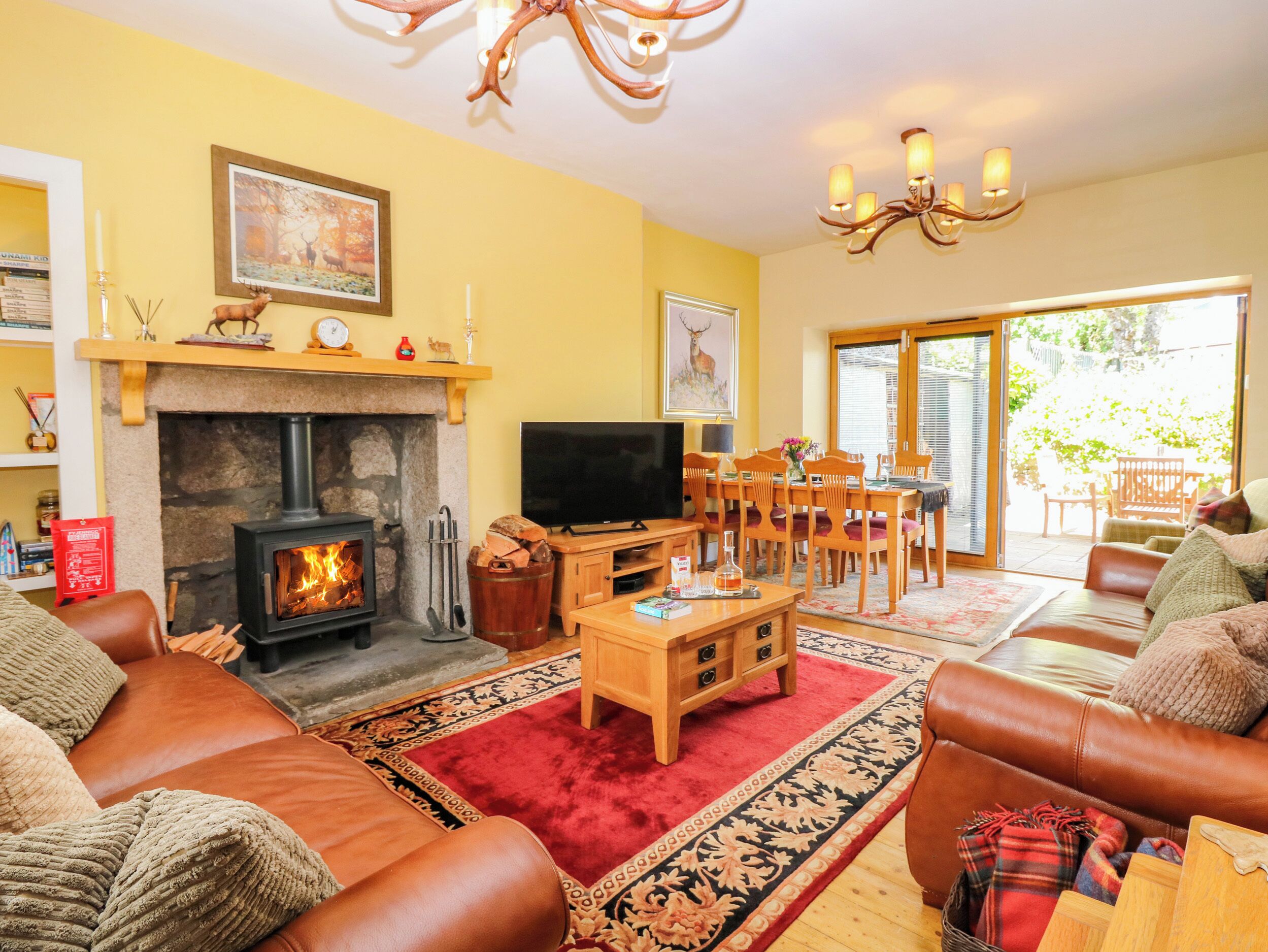 Una sala de estar acogedora con chimenea, sofás de cuero, televisor y un comedor con sillas y mesa.