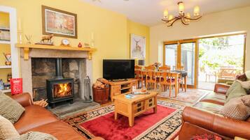 Una sala de estar acogedora con chimenea, sofás de cuero, televisor y un comedor con sillas y mesa.