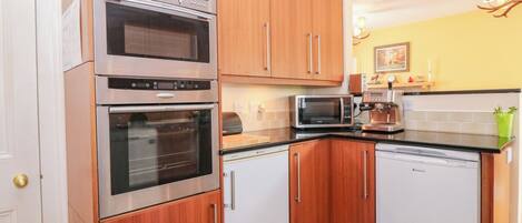 A kitchen with wooden cabinets, stainless steel appliances, a microwave, and a coffee maker.