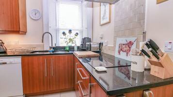 A modern kitchen with wooden cabinets, a black countertop, a sink, a coffee maker, and a knife block.