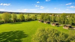 A rural landscape with several wooden cabins arranged in a row. - 2 Bed in Athelington (oc-a35072) (Athelington)