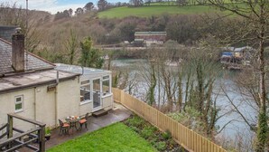 Una casa con un invernadero, un jardín y vista al río.