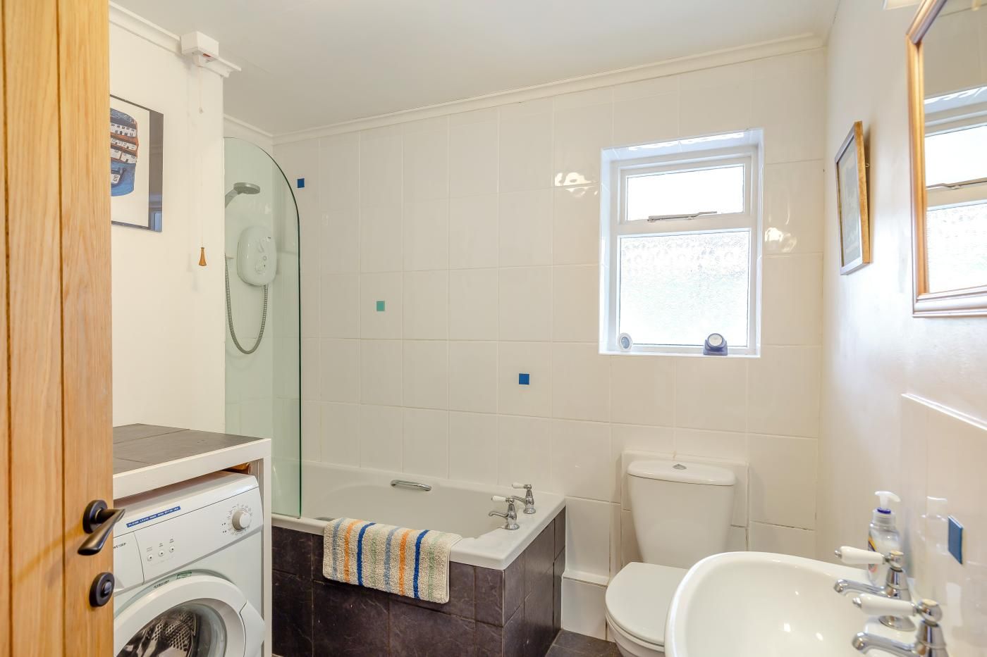 Ein Badezimmer mit Waschmaschine, Badewanne, Toilette und Waschbecken.