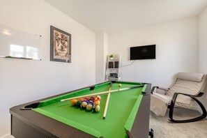 A pool table with balls, a whiteboard, a framed picture, a television, and a reclining chair in a room with white walls. - 3 Bed in Aspatria (oc-h38206) (Aspatria)
