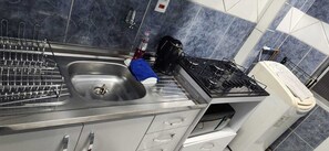 Cuina amb un rentamics d'acer inoxidable, una cuina de gas i una cafetera.
