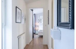 A hallway with framed pictures, a radiator, a bed in the background, and a mirror on the wall. - Seepark Sellin: Komfortable Ferienwohnung Nahe Strand (Sellin)