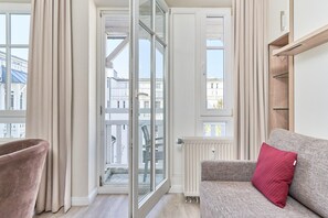 Ein modernes Wohnzimmer mit einer Couch, einem Sessel, einer Glastür, die nach draußen führt, und einer Heizung.