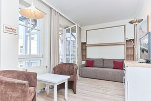 Ein modernes Wohnzimmer mit Sofa, Sessel und Esstisch.