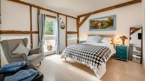 A bedroom with a bed, a chair, a nightstand, a mirror, and a window with curtains. - 3 Bed in Eastbury (oc-t38204) (Eastbury)