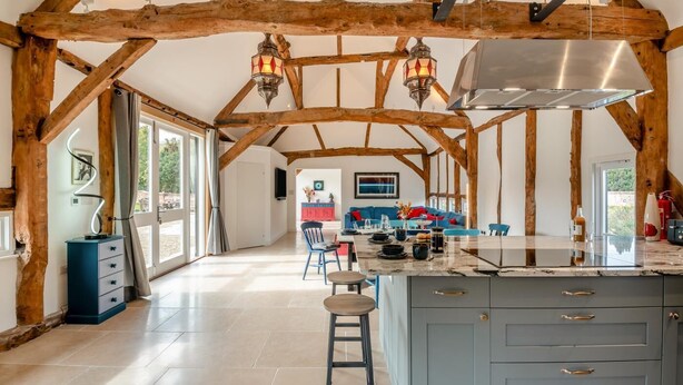 A spacious kitchen with a central island, wooden beams, and pendant lighting. - 3 Bed in Eastbury (oc-t38204) (Eastbury)