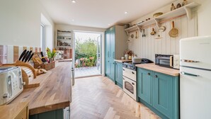 Une cuisine moderne avec des plans de travail en bois, un four encastré et une vue sur l’extérieur.