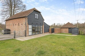 A two-story building with a brick facade, large sliding glass doors, and a small attached garage. - 3 Bed in Peasmarsh (oc-graohf) (Peasmarsh)