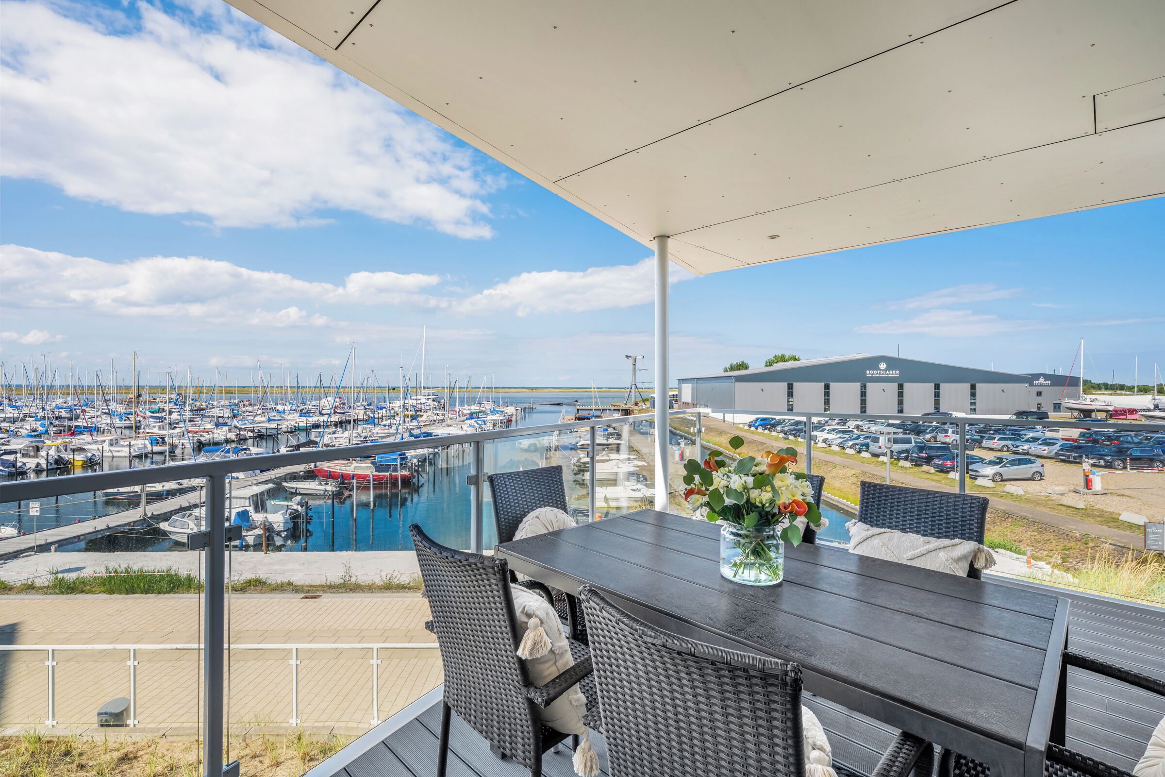 Ein Balkon mit Blick auf einen Jachthafen und ein Gebäude mit der Aufschrift 'Bootslager'.