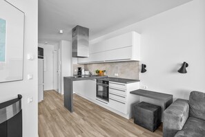 Eine moderne Küche mit weißen Schränken, einem eingebauten Backofen und einer zentralen Kochinsel.