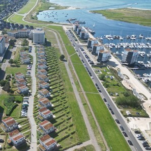 Vista aérea de una zona residencial costera con casas modernas, un puerto deportivo y una carretera.