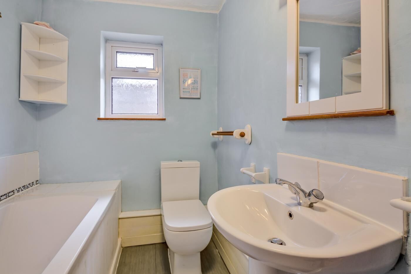 A bathroom with a bathtub, toilet, sink, and a window.