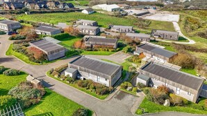 Un quartier résidentiel situé sur la côte, composé de plusieurs maisons individuelles, doté d’une allée pavée et offrant une vue sur la mer.