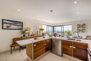 A modern kitchen with a large island, built-in dishwasher, and a view of the outdoors. - 4 Bed in Aberdovey (oc-c35170) (Aberdovey)
