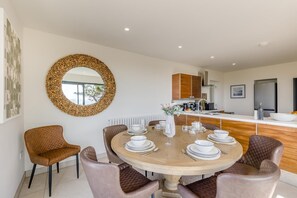 A modern dining area with a round table set for four, surrounded by leather chairs. - 4 Bed in Aberdovey (oc-c35170) (Aberdovey)