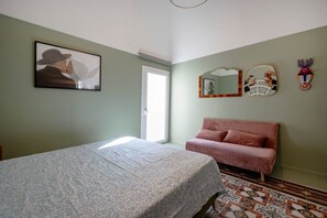 Ett sovrum med en säng, en rosa soffa, ett fönster och en dörr.