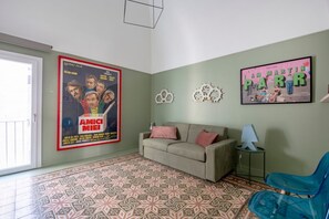 Una sala de estar con piso estampado, un sofá, un sillón azul y dos adornos de pared.