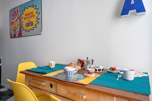 A dining table with a placemat, yellow chairs, and various breakfast items. - GuestHost - Colourful Monopoli Apartment (Monopoli)
