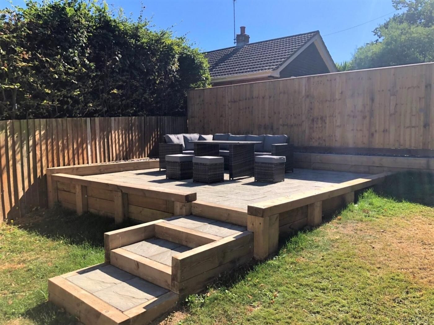 Un jardin avec une terrasse en bois, du mobilier d’extérieur et une piscine.