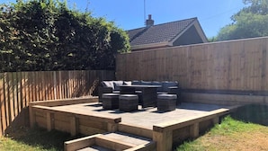 Ein Garten mit einer Holzterrasse, Gartenmöbeln und einem Swimmingpool.