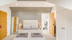Een slaapkamer met een groot bed, nachtkastjes, een kledingkast en een spiegel.