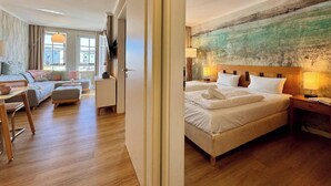 A hotel room with a bed, a desk, a chair, and a view of the outside. - Ferienwohnung in Sellin (Sellin)