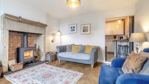 A cozy living room with a fireplace, a sofa, a blue armchair, and a patterned rug. - 1 Bed in Crich (oc-h37533) (Crich)