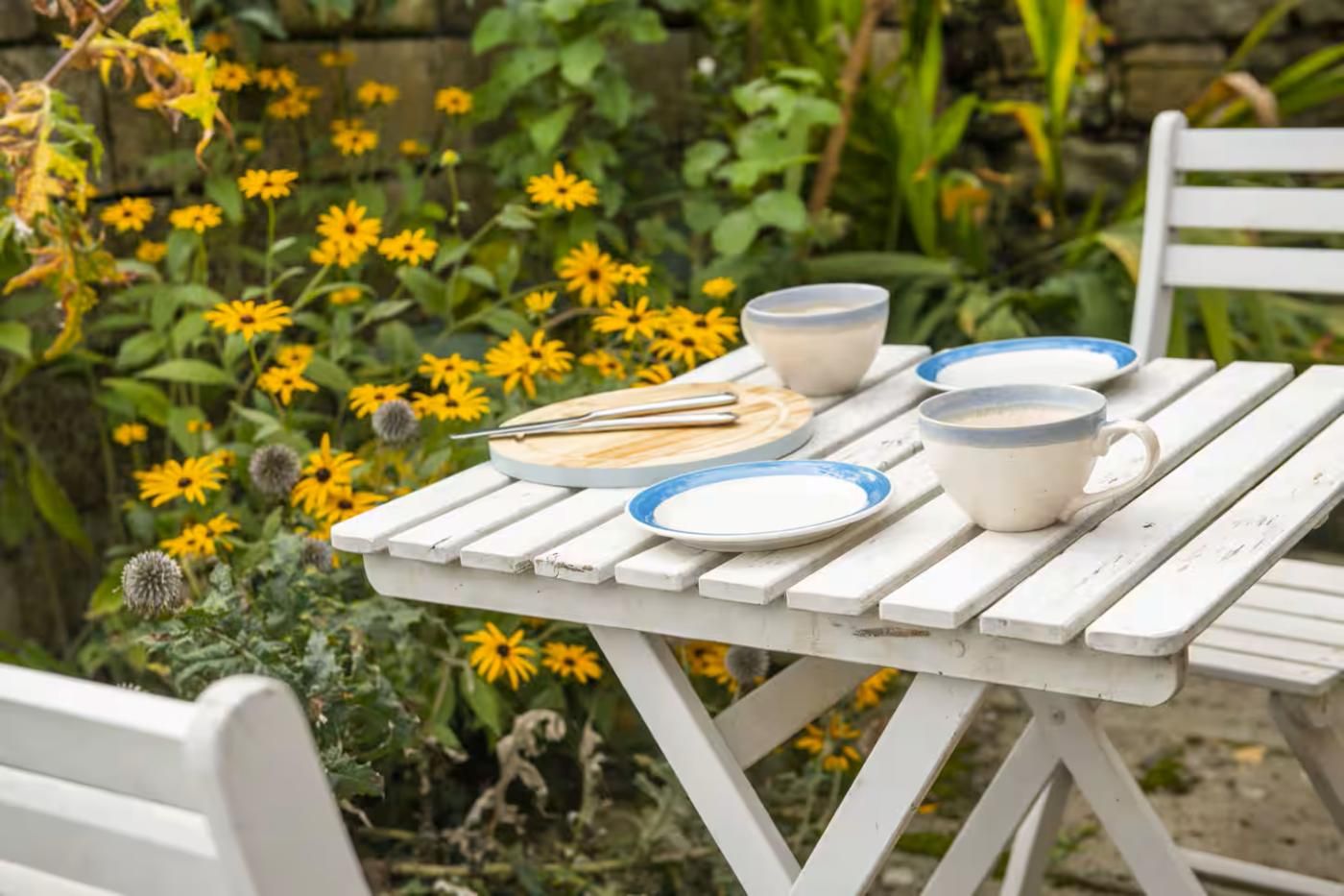 Een witte houten tafel met borden, een kopje en een set kwasten.