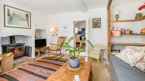 Una sala de estar con chimenea, televisor, sofá, mesa de comedor y cocina al fondo.
