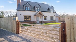 Une maison à deux étages avec une allée d’accès fermée par un portail, une cheminée et un petit porche.