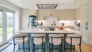 Une cuisine moderne dotée d’un îlot central, de tabourets de bar et offrant une vue sur l’extérieur.
