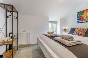 Ein Schlafzimmer mit einem Bett, einem Heizkörper, einem Regal mit Gegenständen und einem Fenster.