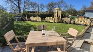 A wooden outdoor table with four chairs, a bottle of wine, and two glasses on a patio. - 2 Bed in Caldbeck (oc-b38644) (Caldbeck)