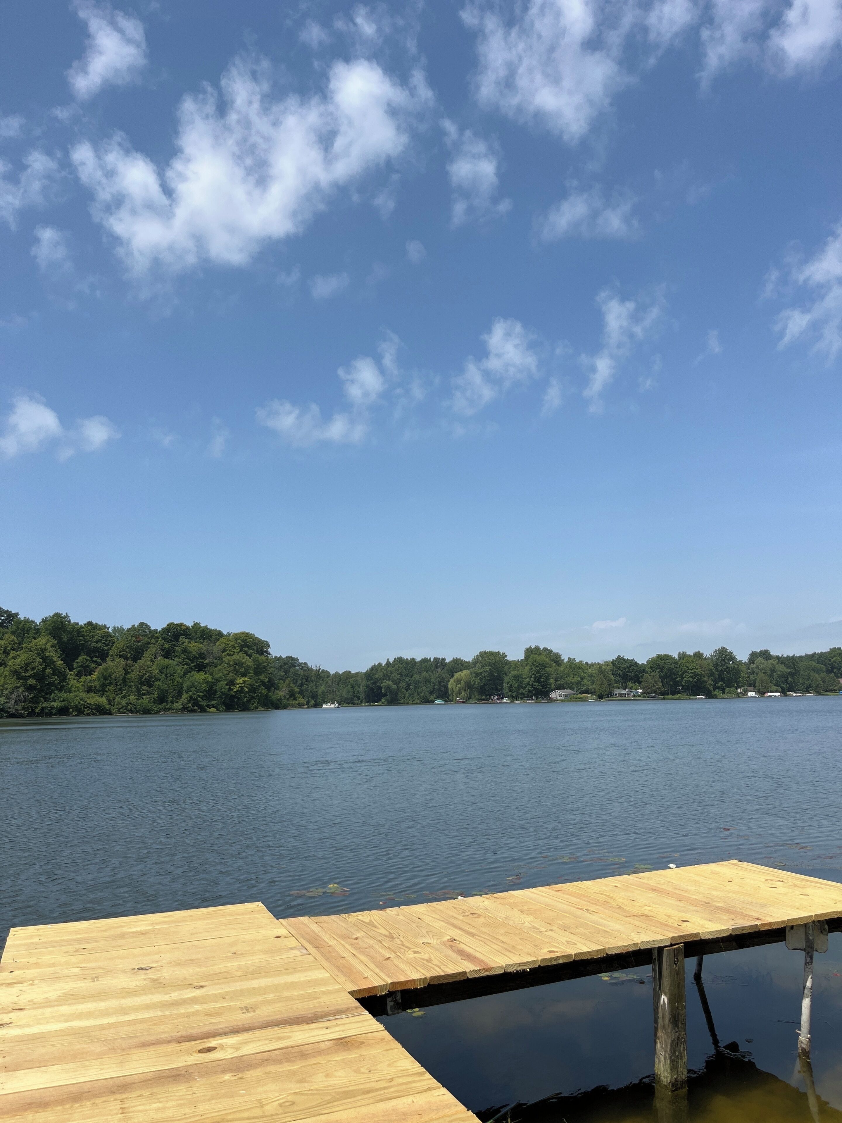 A wooden dock extending into a calm lake with a clear sky above.