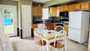 A kitchen with wooden cabinets, a white refrigerator, and a dining table with chairs.