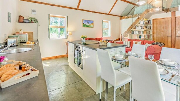 A kitchen with a dining area, wooden beams, a staircase, and a bookshelf. - 2 Bed in Hexham (oc-92527) (Catton)