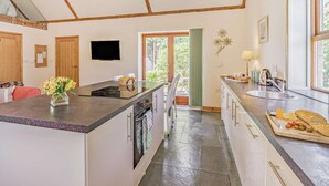 A kitchen with a central island, a dining area with chairs, a built-in oven, and a window with a view. - 2 Bed in Hexham (oc-92527) (Catton)