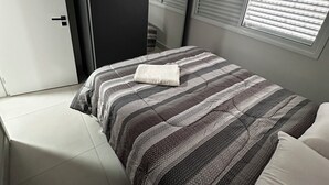 Une chambre à coucher avec un lit, une armoire, une fenêtre avec des stores et une porte.