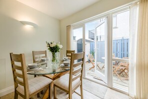 A dining area with a glass table, wooden chairs, and a vase of flowers. - 2 Bed in Seahouses (oc-p39046) (Seahouses)