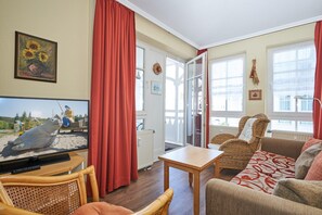 Ein Wohnzimmer mit Fernseher, Korbmöbeln, einer Couch und einem Tisch.