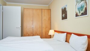 A hotel room with a bed, a wardrobe, a lamp, and two framed pictures on the wall. - Schone Ferienwohnung fur 4 Personen Ostseenah in Sellin (Sellin)