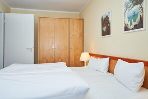 Ein Hotelzimmer mit Bett, Schrank, Lampe und zwei gerahmten Bildern an der Wand.
