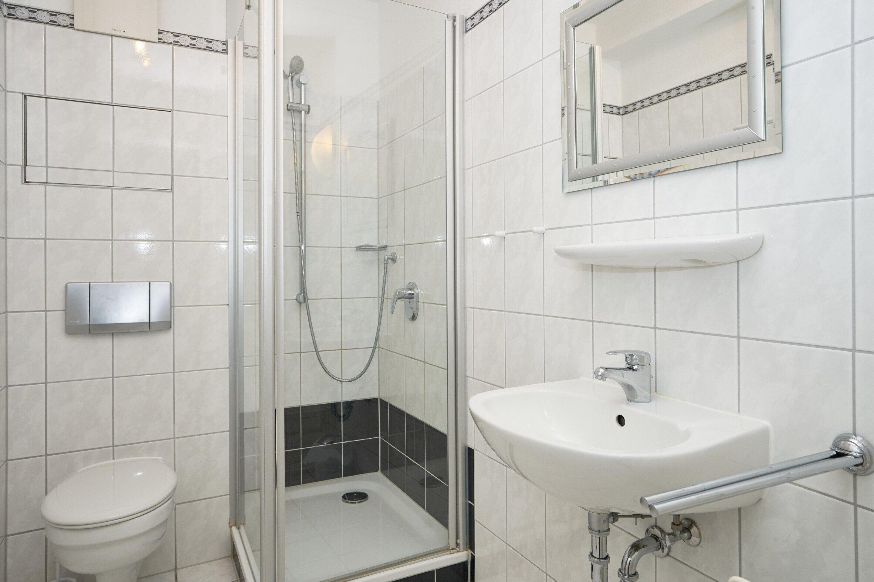 A bathroom with a toilet, a shower, and a sink.