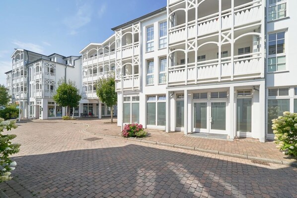 A multi-story building with a symmetrical facade, large windows, and a paved courtyard. - Schone Ferienwohnung fur 4 Personen Ostseenah in Sellin (Sellin)