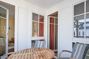 A room with a round wooden table, striped chairs, and large windows with curtains. - Schone Ferienwohnung fur 4 Personen Ostseenah in Sellin (Sellin)