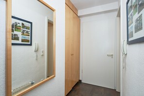 Ein Korridor mit einer Holztür, einer weißen Tür und einem gerahmten Bild an der Wand.